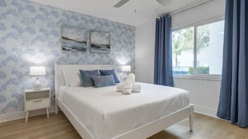 A bedroom with a bed, nightstands, a ceiling fan, and a window with curtains.