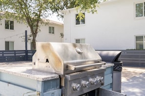 Ein tragbarer Gasgrill mit Bedienfeld, einem Mülleimer und einem Metalltisch.