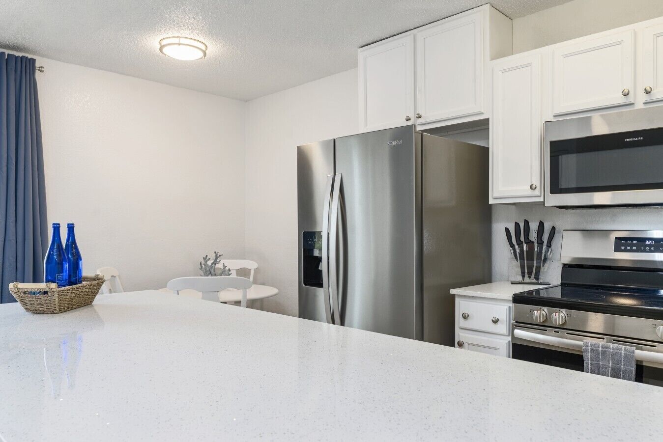 A modern kitchen with stainless steel appliances, a microwave, and a dining area with a white table and chairs.