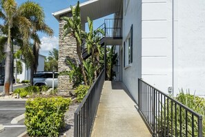 A building with a stone facade, a concrete walkway, and a metal railing.