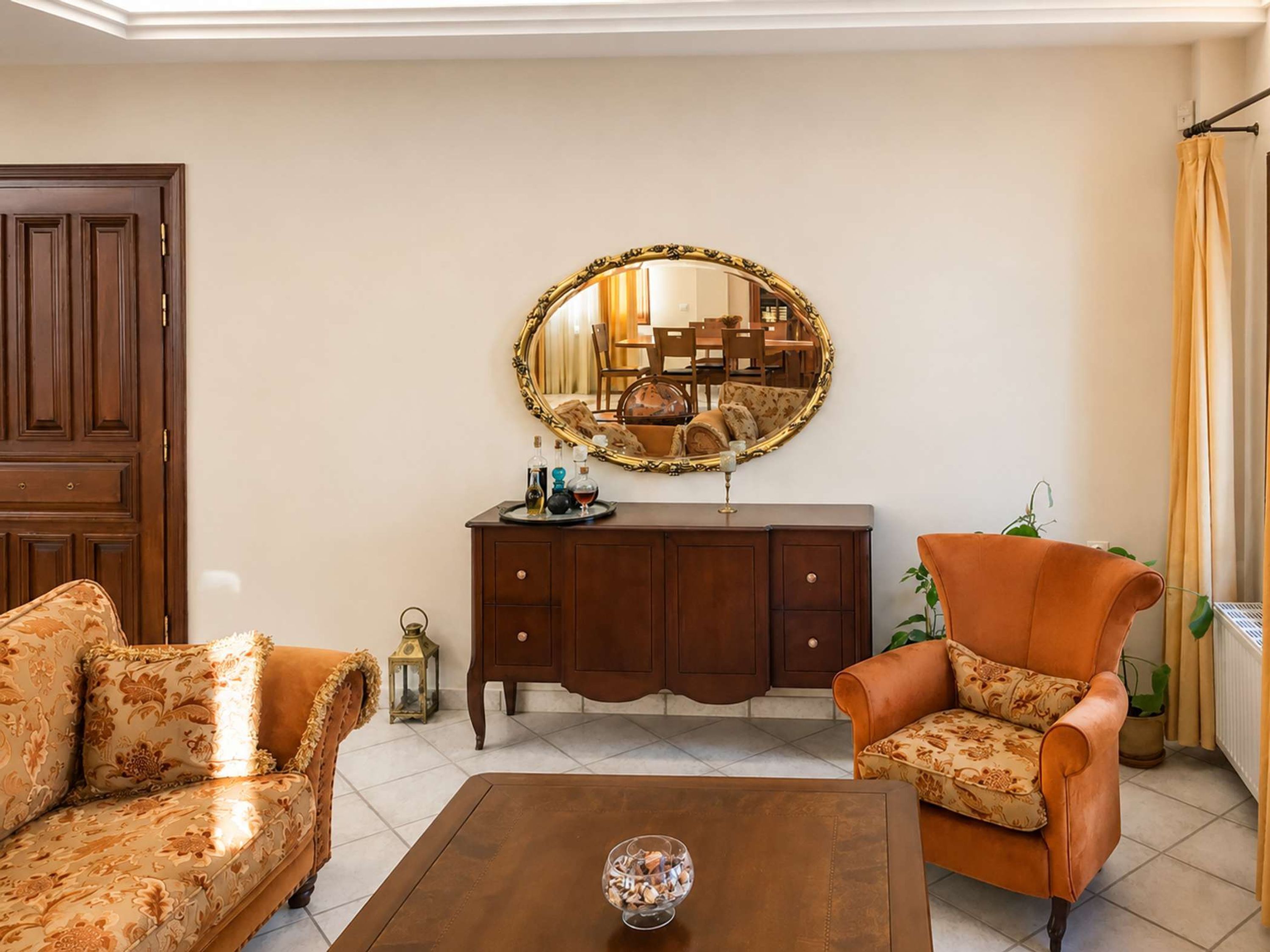 Un salon comprenant un canapé, un fauteuil, une table basse et un miroir décoratif.