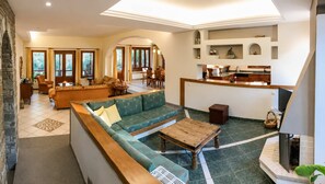 A spacious living area with a green sofa, wooden coffee table, and a dining area with a kitchen in the background. - Mountain Breeze Sanctuary With View Near Volos (Volos)