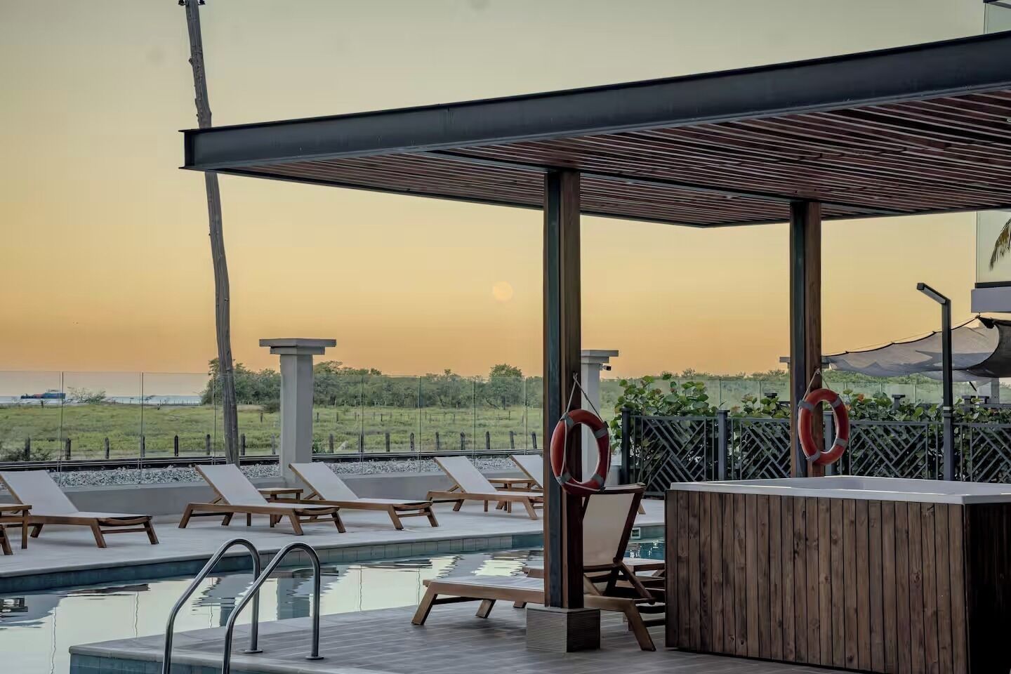 Ein Poolbereich mit Liegestühlen, einer Holzterrasse und Blick auf die Landschaft.