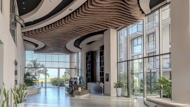 Een ruime lobby met een modern plafondontwerp, grote ramen en kamerplanten.
