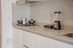 Eine Küche mit einem Gasherd, zwei Töpfen, einer Kaffeemaschine und einem Mixer.
