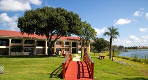 A building with a red roof, a red pathway leading to the entrance, and a body of water in the background. - Harder Hall Resort Club by CoolVacay (Sebring)