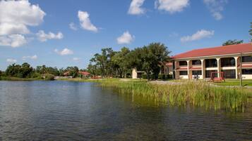 A lakeside hotel with a red roof, multiple windows, and a swing set.