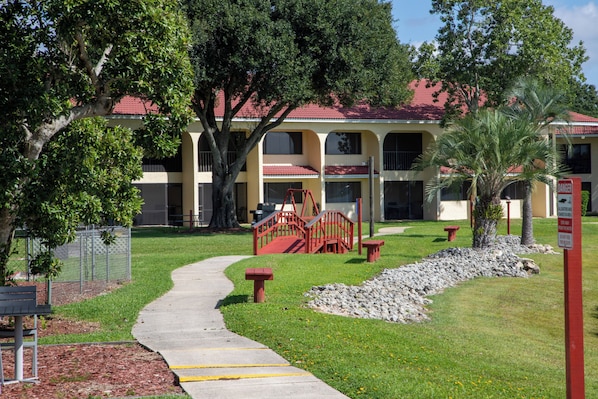 A pathway leading to a building with a red roof, surrounded by trees and a fenced area. - Harder Hall Resort Club by CoolVacay (Sebring)
