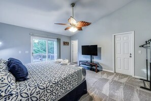 Ein Schlafzimmer mit Bett, Deckenventilator, Fernseher und einer Tür.