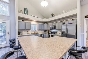 Uma cozinha moderna com uma ilha grande, eletrodomésticos embutidos e banquetas de bar.