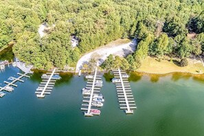 An aerial view of a marina with docks and boats, surrounded by dense forest.