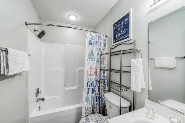 Een badkamer met douche, toilet en wastafel.