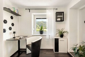 Ein zeitgemäßes Zimmer mit Schreibtisch, Stuhl, Fenster und Topfpflanzen.