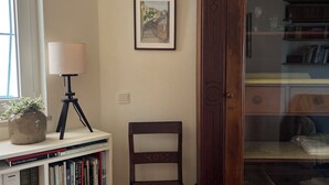 A room with a bookshelf, a lamp, a framed picture, and a wooden cabinet.