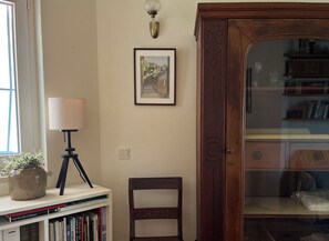 Ein Zimmer mit Bücherregal, Lampe, gerahmtem Bild und Holzschrank.