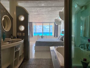 Ein Hotelzimmer mit Balkon, einem großen Bett, einer Badewanne und einem Badezimmer mit Waschbecken und Spiegel.