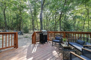 A deck with outdoor furniture, a grill, and a view of a forest. - Pocono Ranch in Bear Creek Lakes - Fire pit, Hammocks, Outdoor Dining (Jim Thorpe)