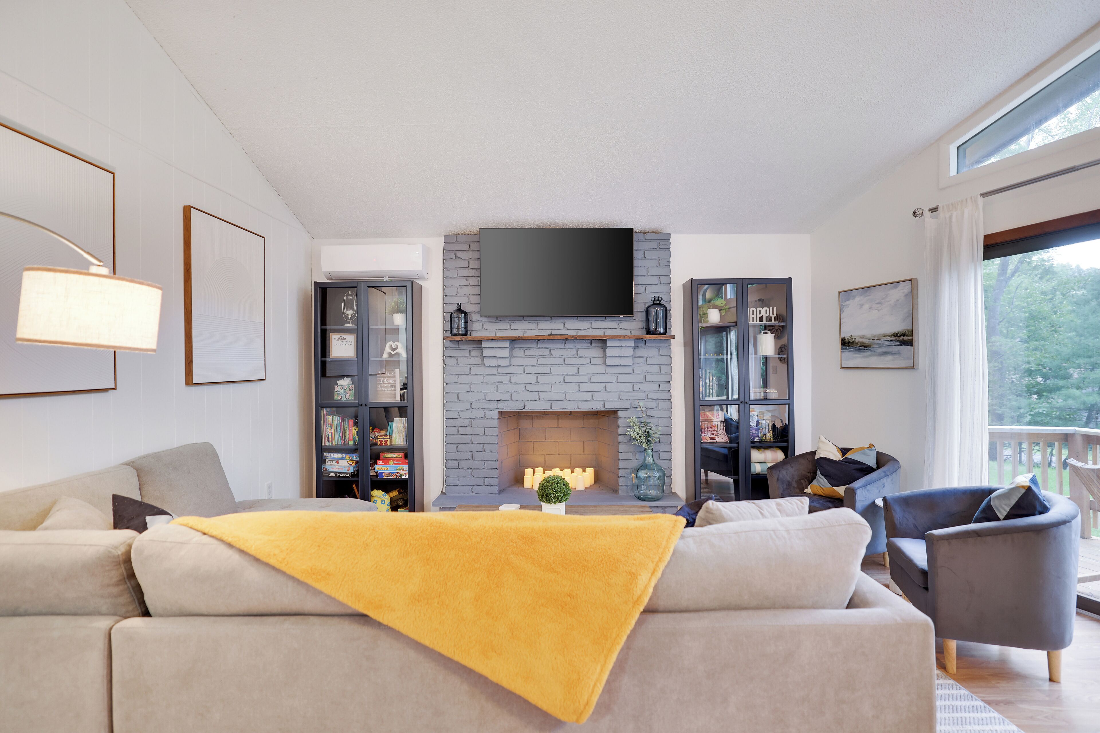 Ein modernes Wohnzimmer mit Kamin, Einbauschränken, einem Flachbildfernseher und einem großen Fenster.