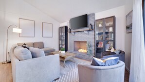 A modern living room with a fireplace, a sofa, a coffee table, and a bookshelf.