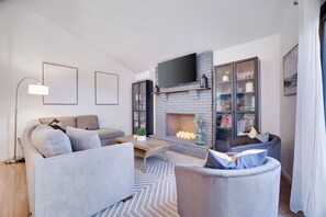 A modern living room with a fireplace, a sofa, a coffee table, and a bookshelf.