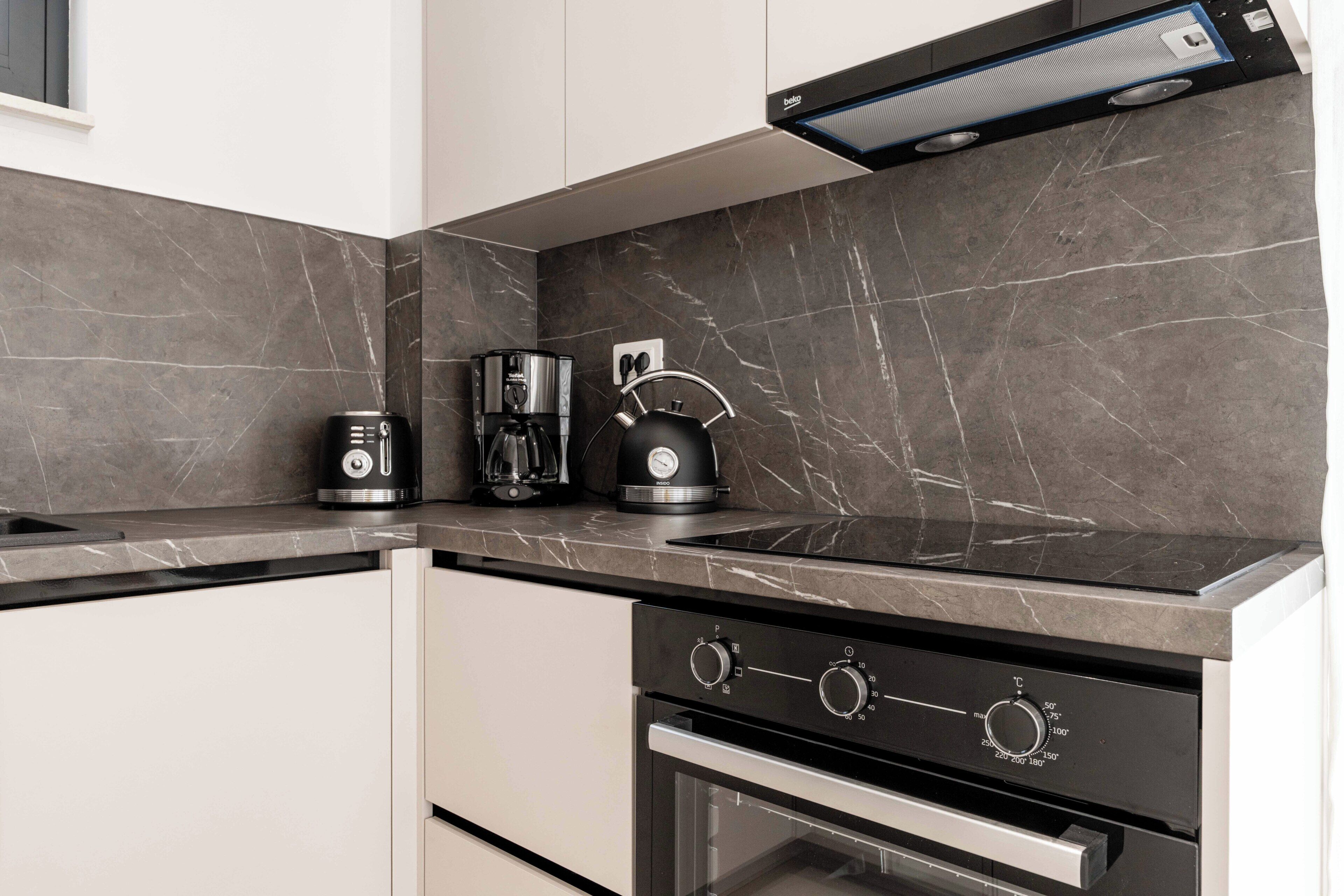 Eine moderne Küche mit eingebautem Backofen, einer Kaffeemaschine und einem Wasserkocher.