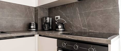 Una cocina moderna con horno integrado, cafetera y tetera.