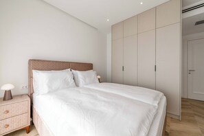 Ein modernes Schlafzimmer mit einem großen Bett, einem Nachttisch und einem Kleiderschrank.