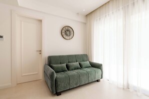 Ein Zimmer mit einem grünen Sofa, einer weißen Tür und einer Wanduhr.