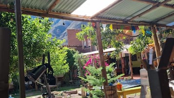 A covered outdoor area with exercise equipment, a wooden deck, and a view of a mountainous landscape.