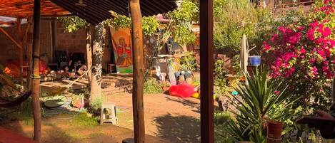 An outdoor seating area with a covered patio, a chalkboard sign advertising events, and a variety of plants and flowers.
