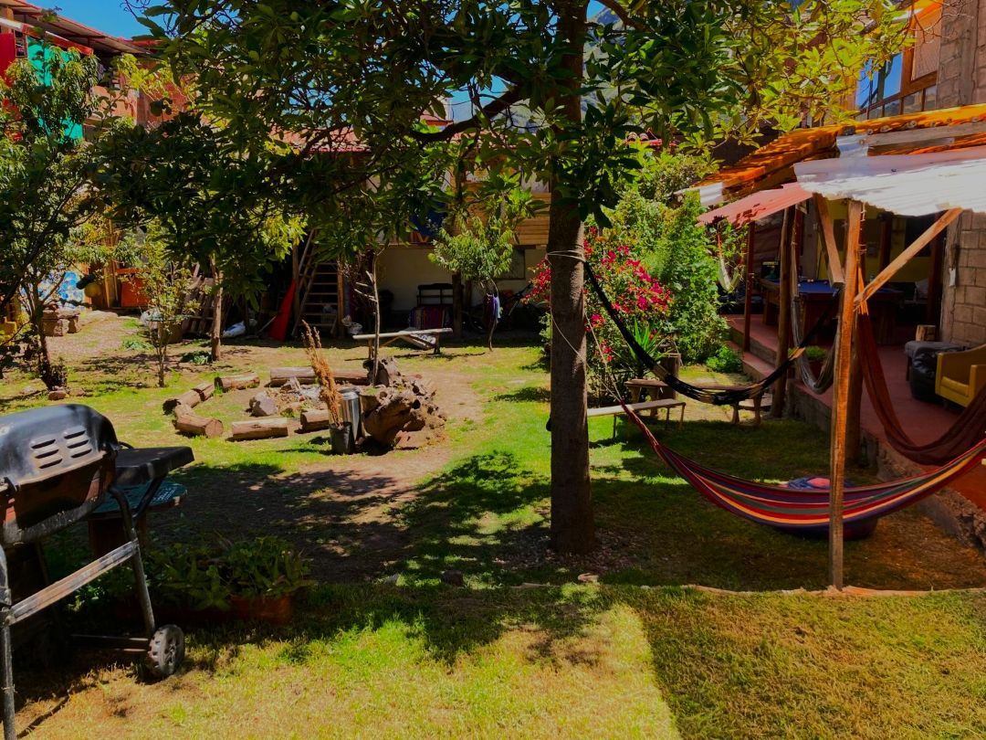 A backyard with a hammock, a grill, and a picnic table.