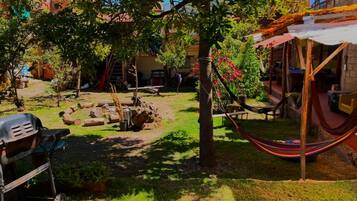 A backyard with a hammock, a grill, and a picnic table.