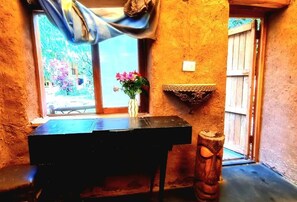A rustic room with a wooden table, a vase with flowers, and a small shelf. - Kamanti Hostel (Pisac)