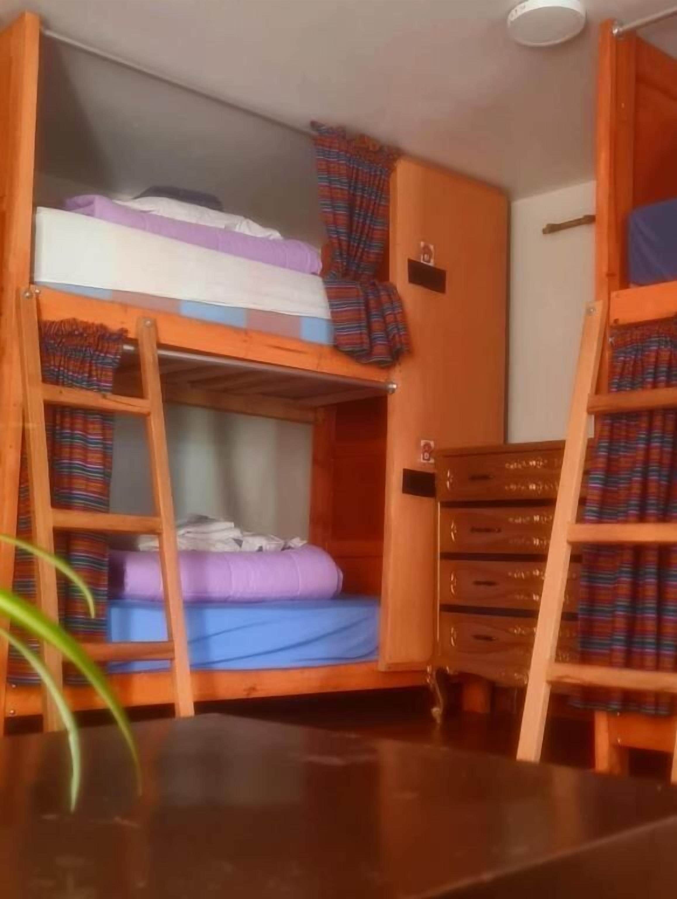 Une chambre avec un lit superposé, une échelle, une petite table et une armoire.