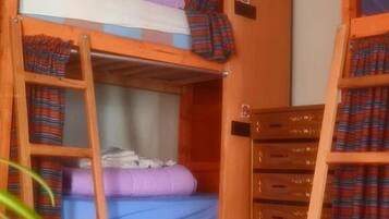 Une chambre avec un lit superposé, une échelle, une petite table et une armoire.