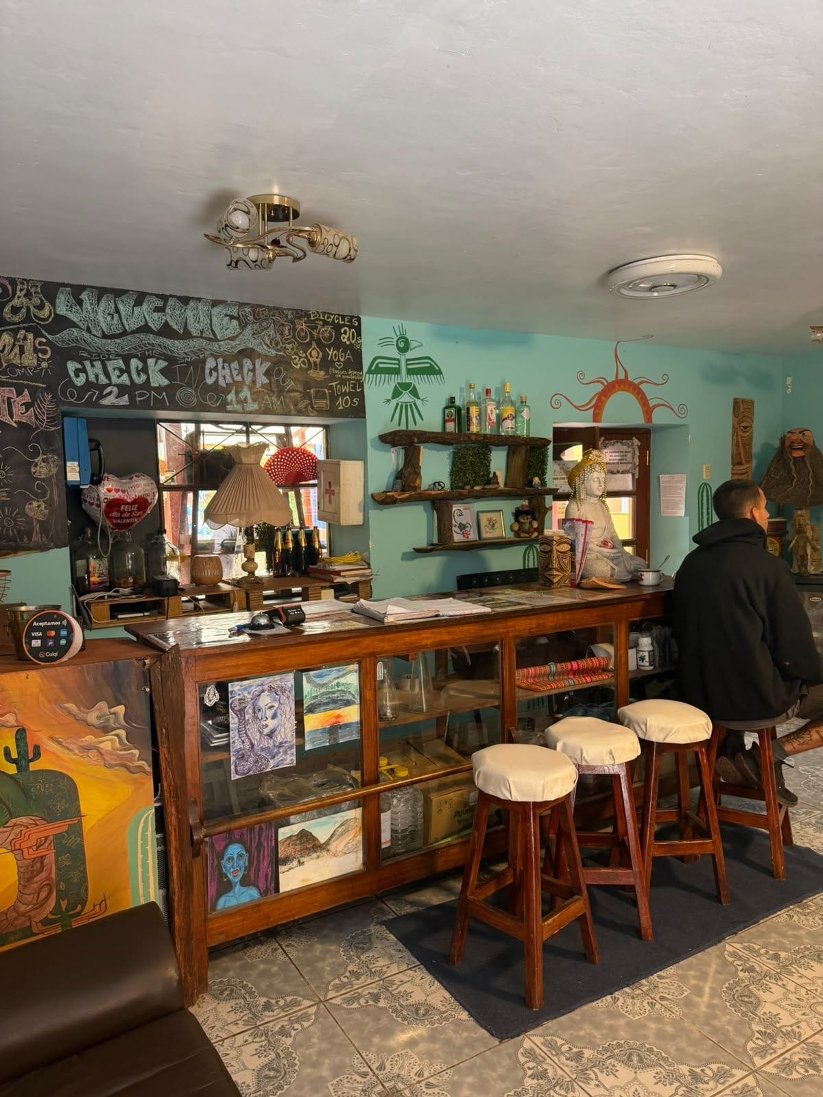 Una zona de bar con taburetes, una barra y varios objetos en estantes.