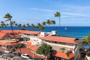 A coastal town with buildings, palm trees, and a view of the ocean. - Kona Plaza#417: Top Floor, Downtown! (Kailua-Kona)