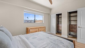 Un dormitorio con cama, ventana, ventilador de techo y armario con espejo.