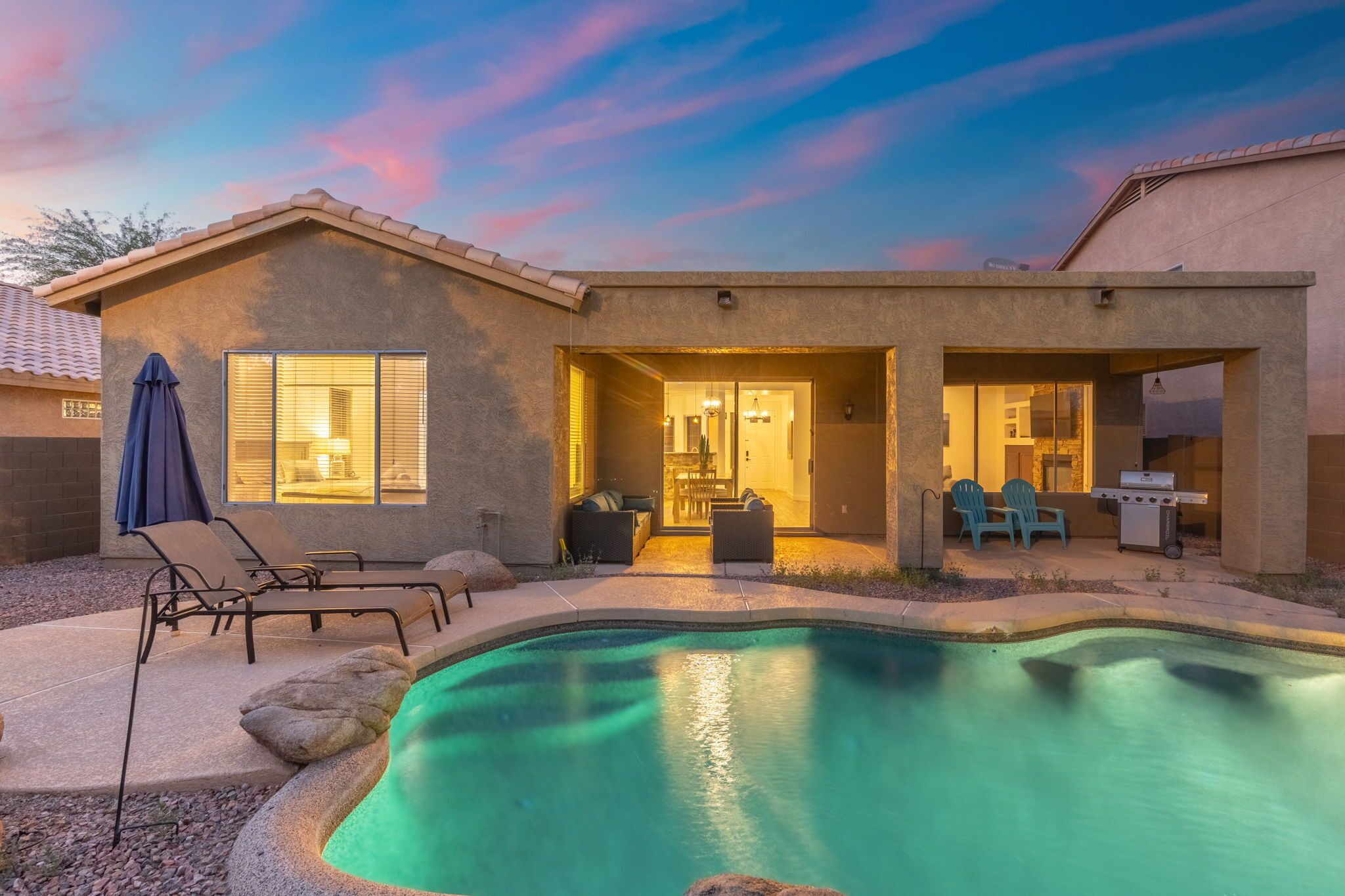 A modern house with a swimming pool, outdoor seating, and a patio area.