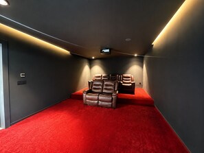 A home theater room with red carpet, leather recliners, and a flat-screen TV mounted on the ceiling. - Architect-designed villa - 5 suites - movie theater & hammam (Marrakech)