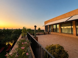 A modern building with a flat roof, large windows, and a balcony with potted plants. - Architect-designed villa - 5 suites - movie theater & hammam (Marrakech)