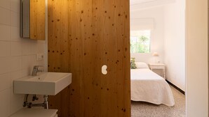 Een moderne badkamer met een houten deur, een wit wastafelmeubel en een spiegel.