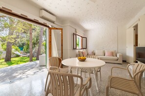 A modern living room with a round table, white chairs, a sofa, and a TV. - Sa Marina by Rentallorca (Son Serra de Marina)