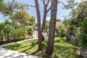 A garden with trees, a hammock, and a stone wall. - Sa Marina by Rentallorca (Son Serra de Marina)
