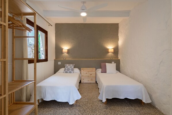 A small, compact room with two single beds, a wooden wardrobe, a ceiling fan, and two wall-mounted lamps. - Sa Marina by Rentallorca (Son Serra de Marina)