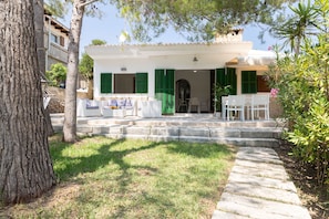 A white building with green shutters, a stone staircase leading to a covered porch, and outdoor furniture. - Sa Marina by Rentallorca (Son Serra de Marina)