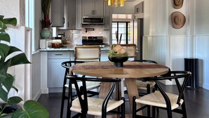 Een moderne keuken met witte kasten, een magnetron en een eethoek met een ronde tafel en stoelen.