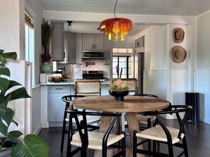 A modern kitchen with white cabinets, a microwave, and a dining area with a round table and chairs. - 2 bed 1 bath bungalow in Central Austin. Pet friendly! Minutes to Downtown. (Austin)