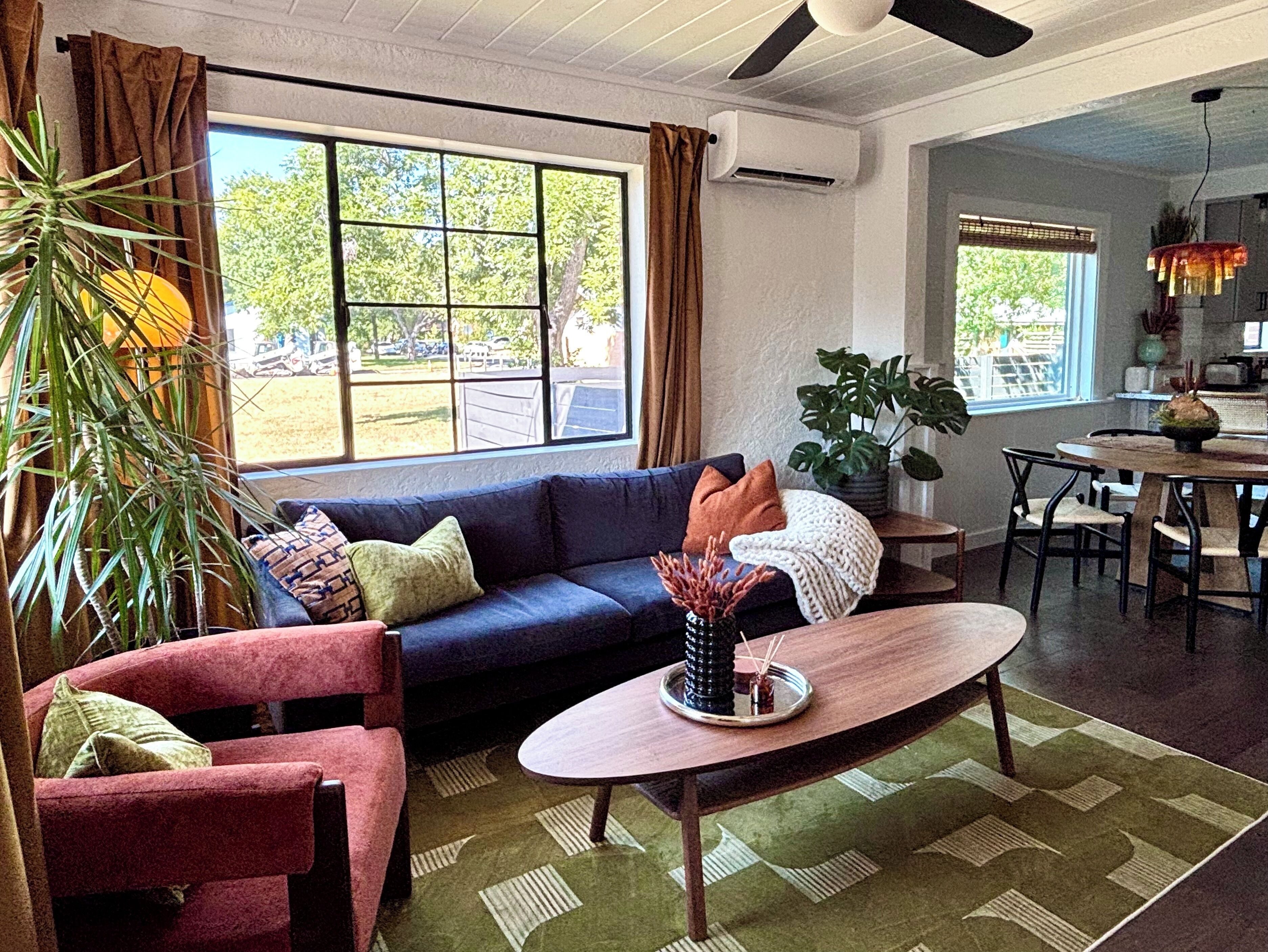A living room with a sofa, armchairs, a coffee table, and a dining area with chairs.