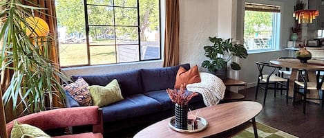 A living room with a sofa, armchairs, a coffee table, and a dining area with chairs.
